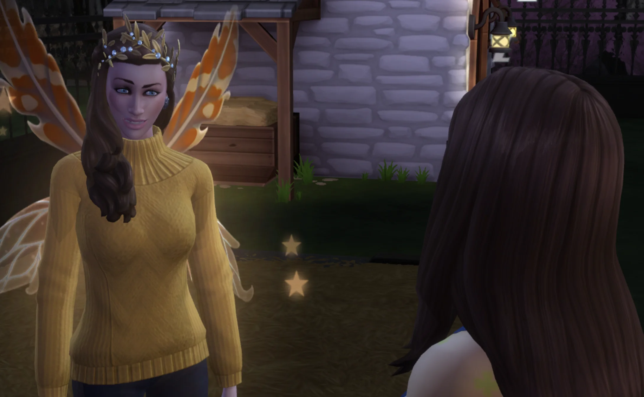 screenshot from Sims 4 of my sim, with long brown hair and a yellow sweater in mid conversation with someone in front of her, who also has long brown hair, while they stand outside near a horse's bed and a stone animal pen