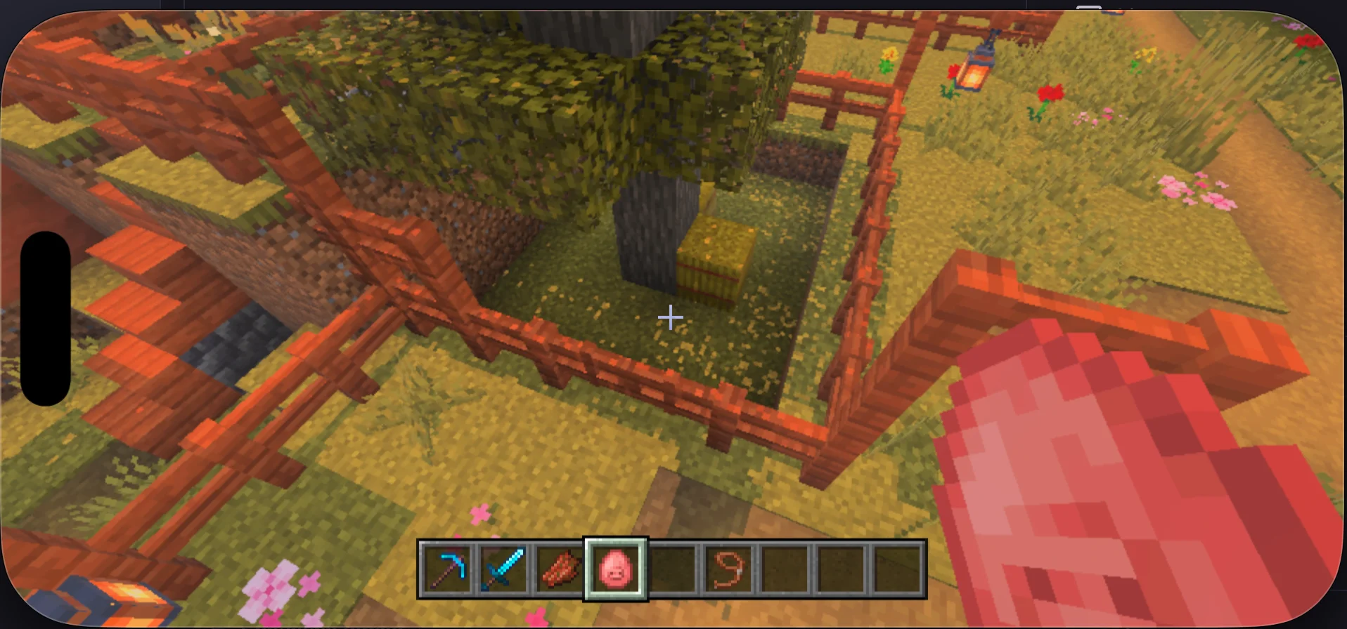A screenshot from Minecraft mobile on iOS of me floating in front of a fence and a tree in the grass